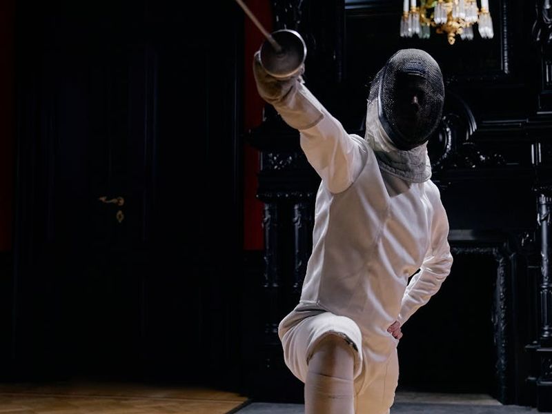 Person in a dynamic yet graceful movement pose indoors.